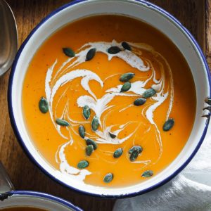 This 30-Minute Butternut squash soup is so comforting and perfect to warm you up! Healthy, light and the toppings elevate it a bit more while being super simple. It has toasted pumpkin seeds for a crunchy texture contrast and that fancy yet easy cream (or yoghurt) swirls for creaminess. The soup can be seen served in an enamel bowl with the toppings. It's a close up shot to see the toppings properly.