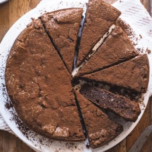 This Gluten-Free Chocolate Almond Cake is flourless thanks to using ground almonds, which not only give the cake a top texture but also add a delish flavour. It's moist and has a crinkle top, like the one of a good brownie. It's easy to put together and you can top it with some cocoa powder for a final touch. Overhead shot. The right side is sliced into 6 triangles and one is laying on its side so the interior of the cake can be seen.