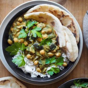 This 30 Minute Chickpea Aubergine Curry recipe is perfect for a weeknight meal. It's quick to make, simple and incredibly! Serve over basmati rice and with a side bread to top it up a notch. And by the way, it's naturally is vegan, gluten-free and lactose-free. What else can one ask for? In this overhead shot we can see the curry served over rice on a plate with some flat bread.