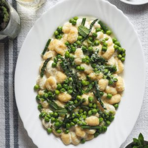Spring on a plate with these 10-Minute Creamy Gnocchi with Peas and Asparagus. It's really that quick and so delicious! To speed things up I use pre-made gnocchi; then, there are bright peas and asparagus to make the most of seasonal ingredients. These are mixed with a creamy lemony garlicky white sauce that is to die for. And finally, some grated parmesan and mint leaves to top it all. | Paula's Apron Recipe