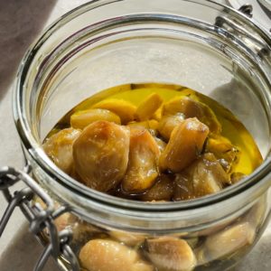 This Garlic Confit recipe is going to become your new pantry staple because it's so easy and confited garlic is so spectacular and versatile. You just need a few heads of garlic, your favourite spices and herbs, lots of olive oil and 30 minutes. The result is a scrumptious sort of sweet spreadable garlic that you can use in a thousand ways. As a bonus, you get garlic-infused oil! | Paula's Apron Recipe