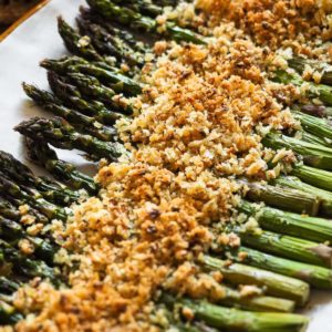 These Garlicky Lemony Crispy Roasted Asparagus are an ideal side dish during spring. Imagine grilled asparagus (because a high-temperature oven cooks them in a similar way :P), but with extra crunchiness and flavour thanks to a garlic, lemon and hazelnut topping! It's perfect to change from classic roasted asparagus, and even those who say they're not the biggest fans of asparagus can't resist these. | Paula's Apron Recipe