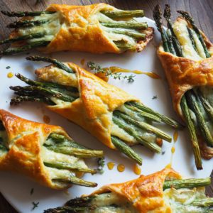 These Asparagus and Brie Flaky Pastries are so springy and easy to put together: crispy homemade pastry, brie that melts in the oven (and your mouth) and seasonal asparagus. The thyme honey which comes along only adds to that. They make an ideal brunch, appetizer or starter and let me assure you that it's one of those recipes that make people go speechless. These make a real spring hit! | Paula's Apron Recipe